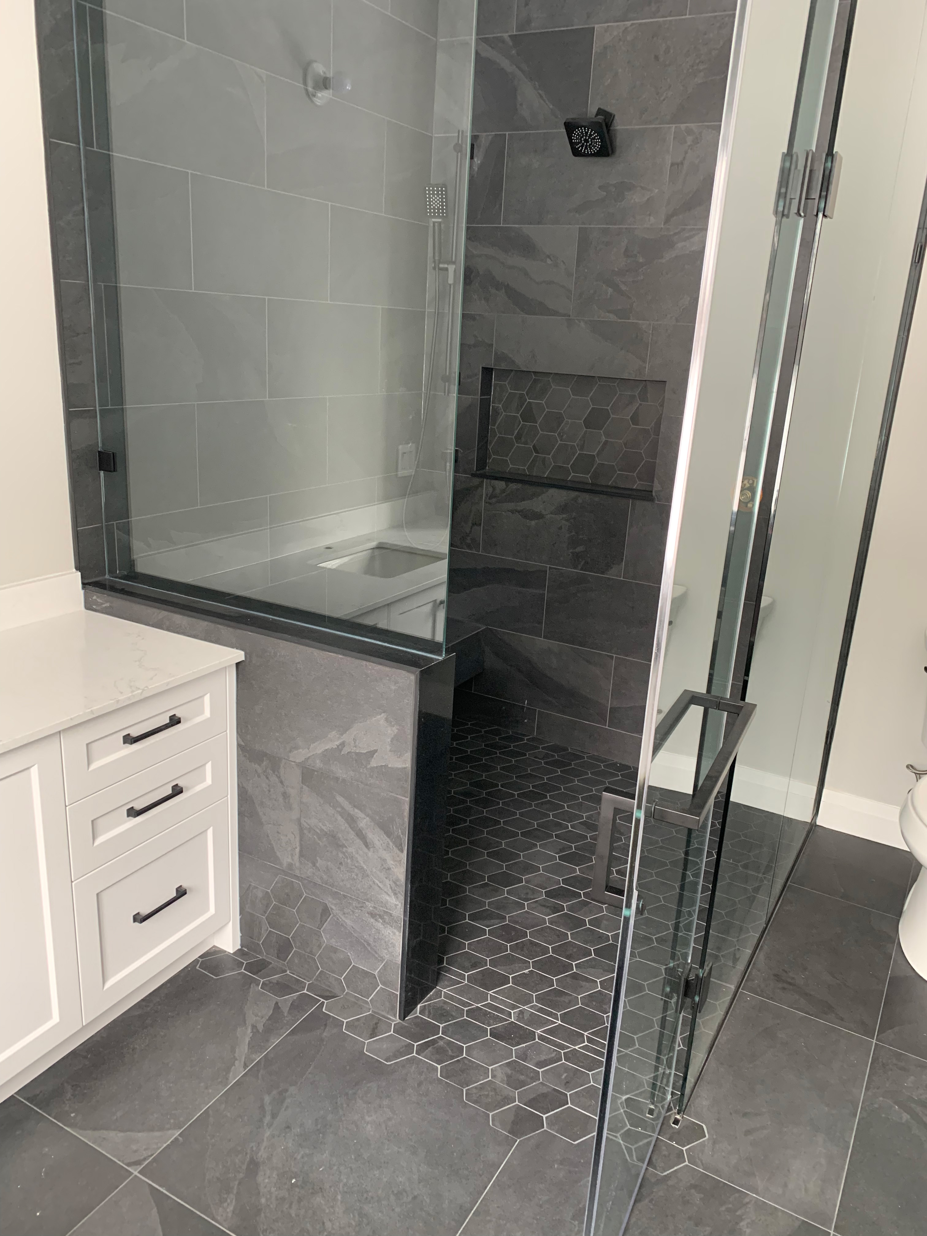 Walk-in shower with gray tile and glass door
